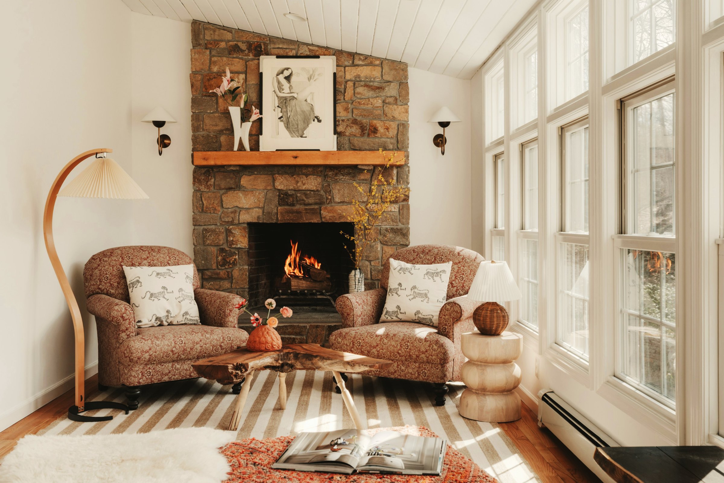 A living room with a stone fireplace staged with subtle fall accents